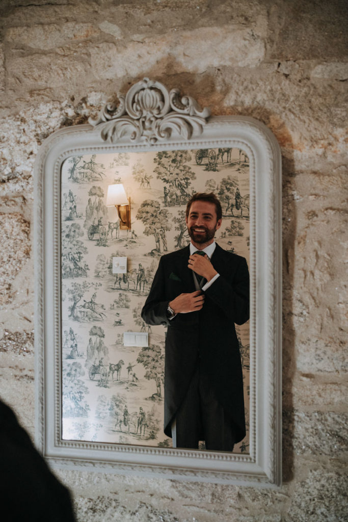 foto de un novio en la boda prepárandose delante del espejo en una suite en A Quinta da Auga